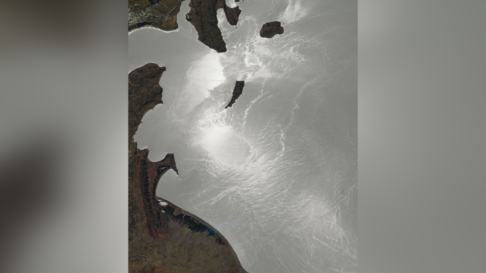 A silvery surface of a large lake is in front of a brown surface