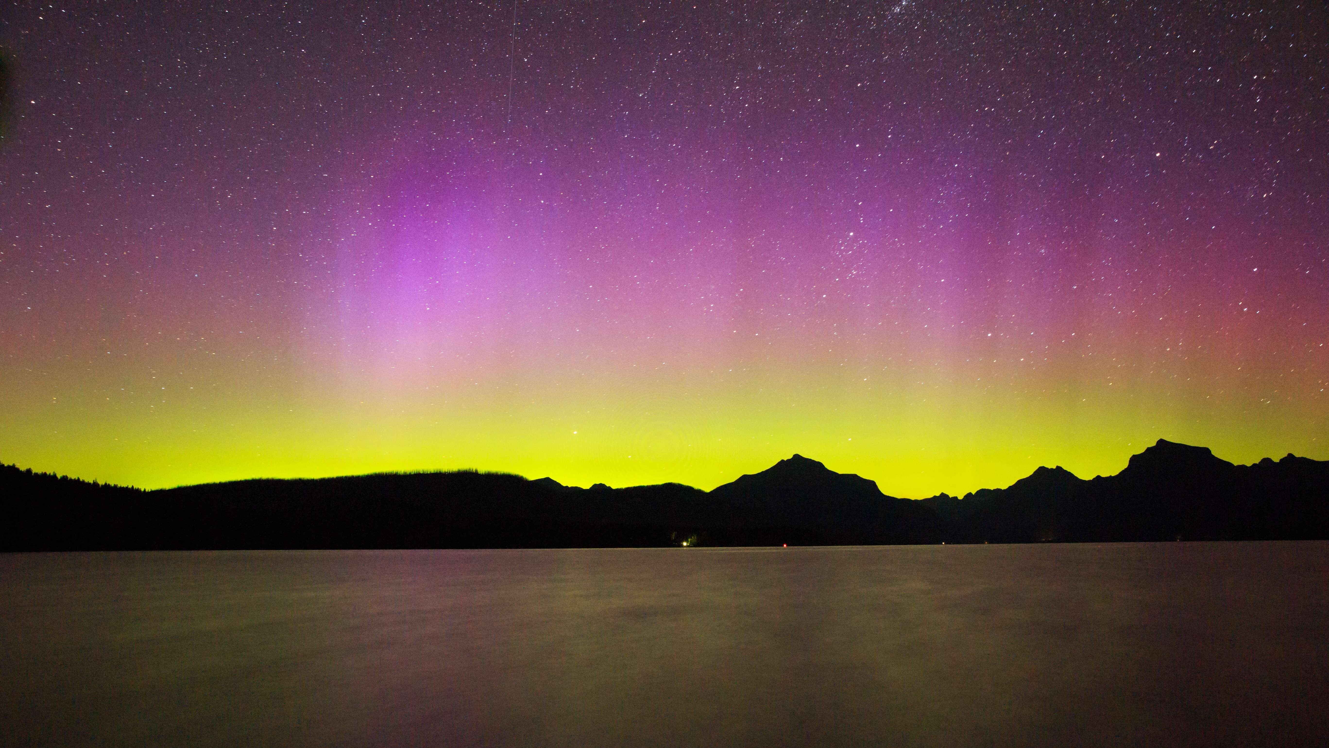 northern lights above Lake MacDonald in Glacier National Park Rocky Mountains, Montana. The aurora appears as curtains of purple and green light