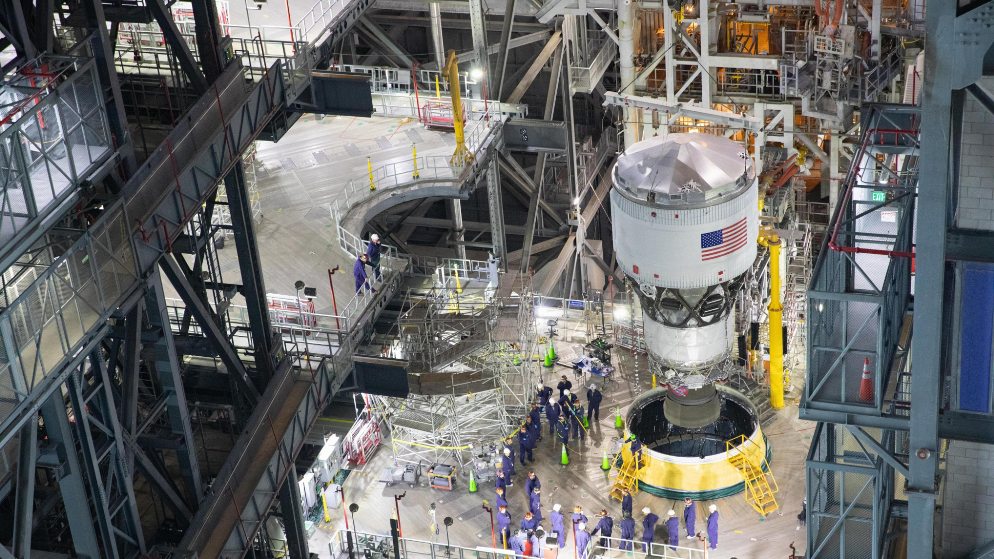 A white cylinder with an american flag is lowered into a fitting hole on a raised metal platform.