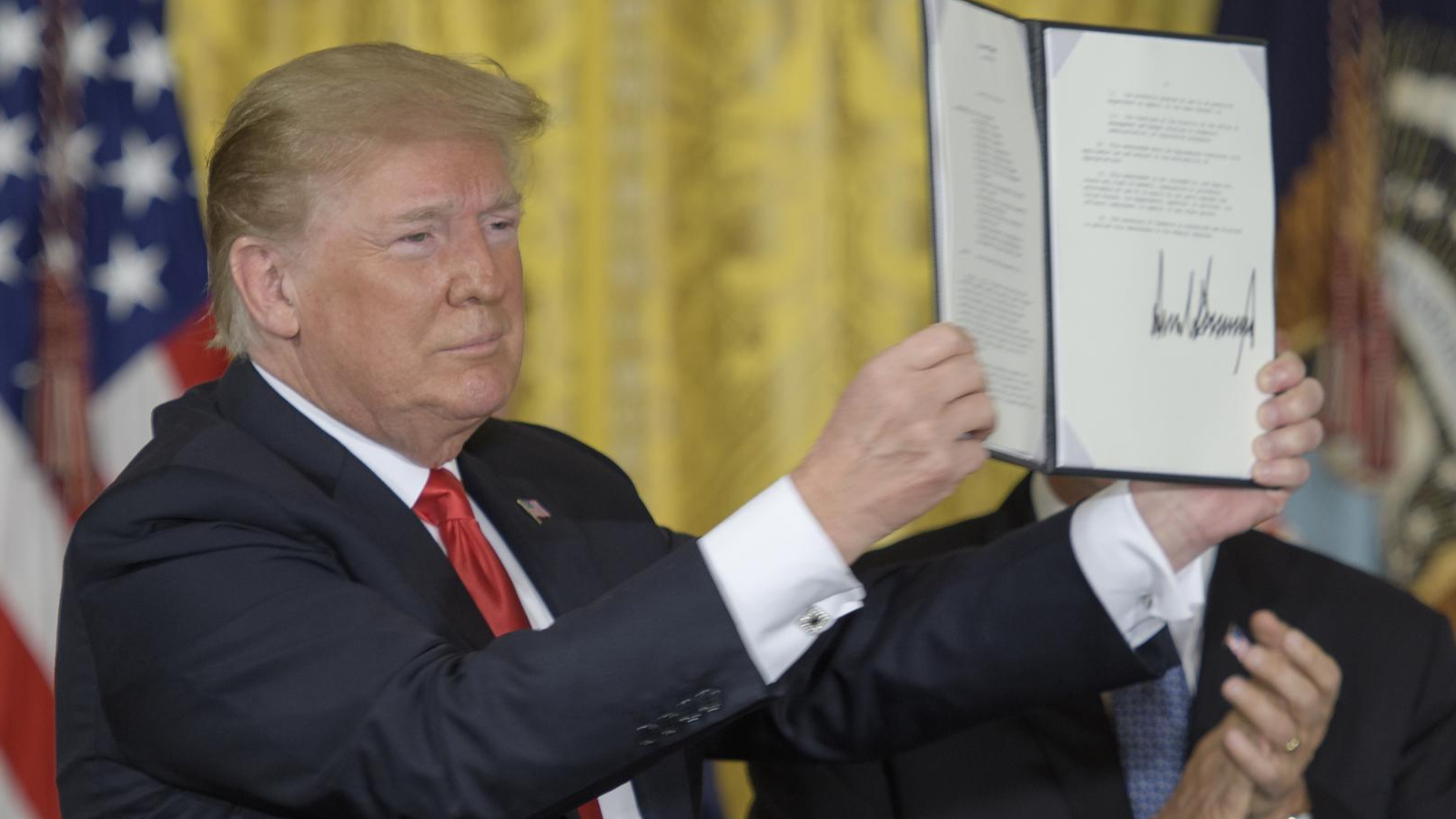 A man holds a piece of signed paper